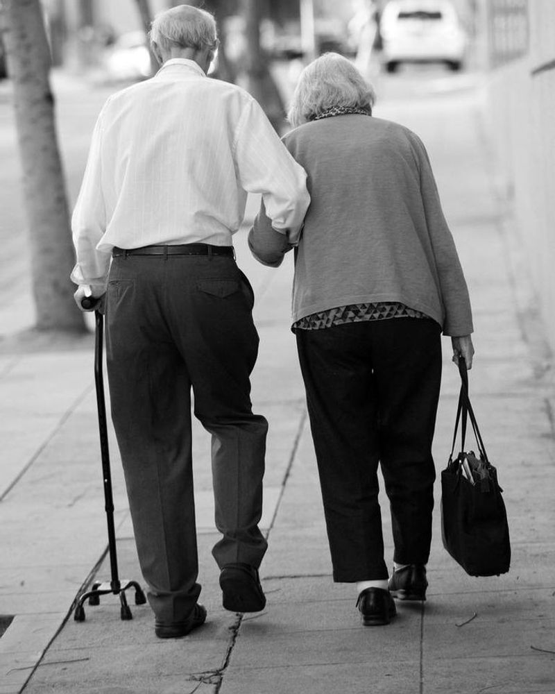 Elderly couple walking with support cane
